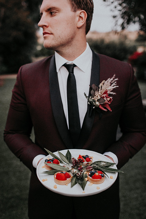 orange-county-vow-groom-holding-the-plate-groom-in-a-burgundy-tuxedo-with-a-black-shawl-lapel