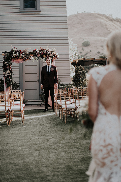 orange-county-vow-renewal-bride-walking-down-the-aisle-bride-in-a-lace-modern-fitted-gown-with-a-nude-underlay-groom-in-a-burgundy-tuxedo-with-a-black-shawl-lapel