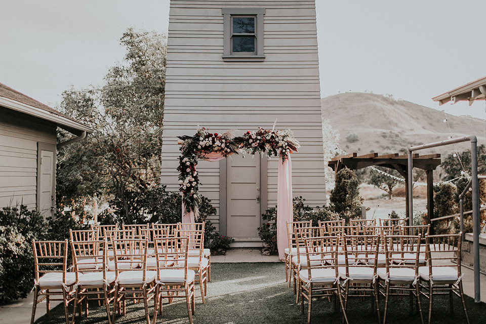 orange-county-vow-renewal-brode-and-groom-walking-and-looking-at-each-other-bride-in-a-lace-modern-fitted-gown-with-a-nude-underlay-groom-in-a-burgundy-tuxedo-with-a-black-shawl-lapel