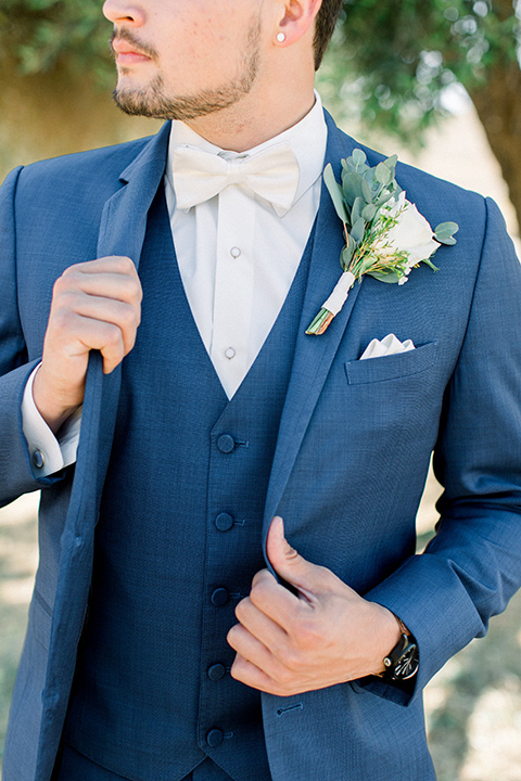 the groom in a dark blue suit with a white bow tie