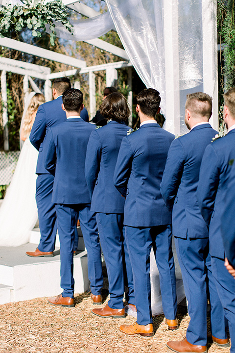  groomsmen in dark blue suits at ceremony 