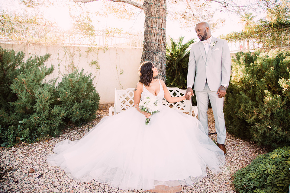 little-chapel-on-the-corner-las-vegas-wedding-shoot-bride-sitting-groom-standing-the-bride-wore-a-tulle-ballgown-with-skinny-straps-and-the-groom-wore-a-heather-grey-suit