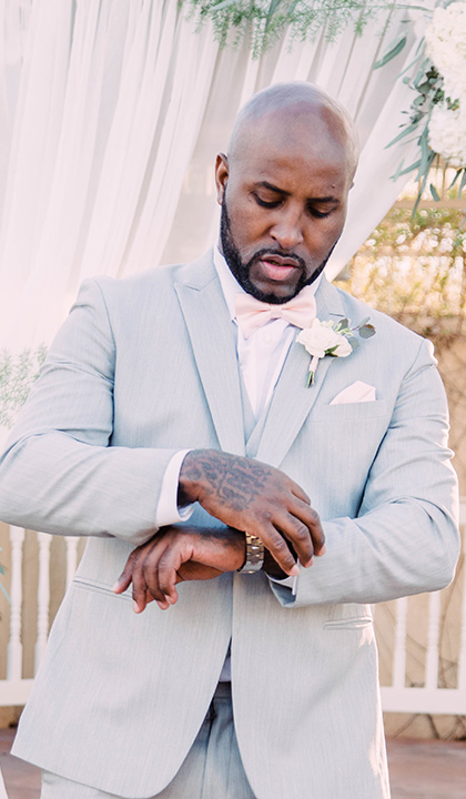 little-chapel-on-the-corner-las-vegas-wedding-shoot-groom-adjusting-watch-while-wearing-a-light-grey-suit-and-ink-bow-tie