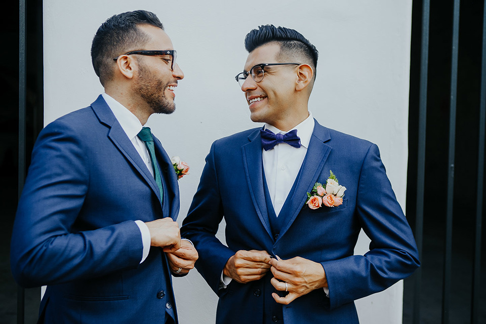 loquita-shoot-grooms-laughing-looking-at-each-other-grooms-in-cobalt-blue-suits-with-one-with-a-green-tie-and-the-other-with-a-blue-bow