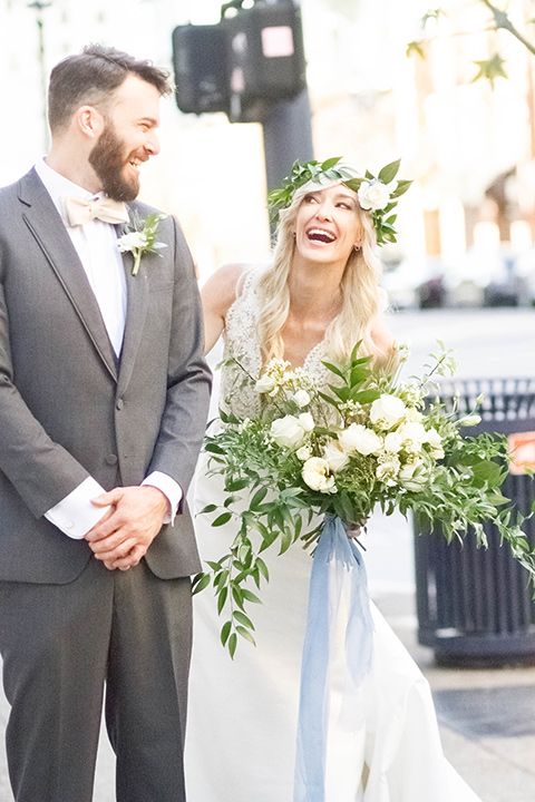 luce-loft-bride-and-groom-laughing-outside-bride-in-a-fit-and-flare-gown-with-straps-groom-in-a-charcoal-suit-with-champagne-bow-tie