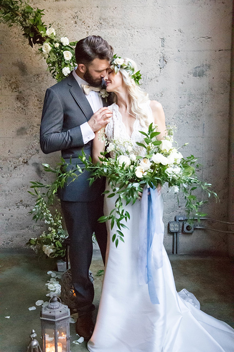 luce-loft-couple-at-ceremony-space-bride-in-a-fit-and-flare-gown-with-straps-groom-in-a-charcoal-suit-with-champagne-bow-tie