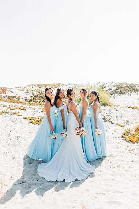 San-Diego-Beach-wedding-bridesmaids-back-to-camera-in-blue-flowing-gowns-and-the-bride-in-a-lace-fitted-gown