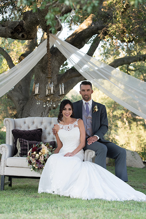 milagro-farms-shoot-bride-and-groom-in-outside-space-bride-in-a-fitted-lace-gown-with-straps-groom-in-a-charcoal-suit-with-a-purple-tie