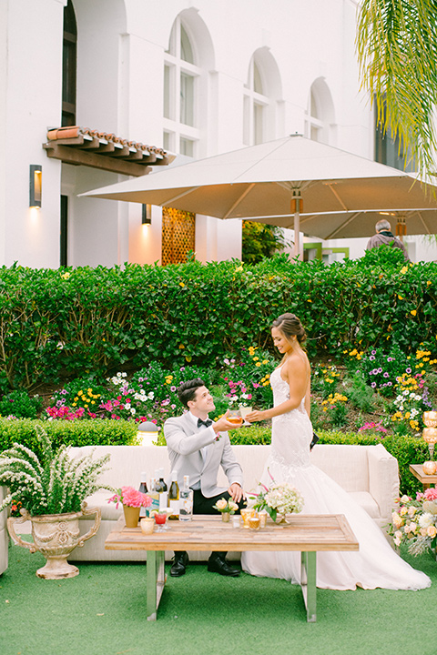 omni-la-costa-groom-sitting-bride-standing-bride-wearing-a-lace-fitted-gown-with-mermaid-style-with-thin-straps-groom-with-light-grey-jacket-with-black-pants-black-polka-dot-bowtie