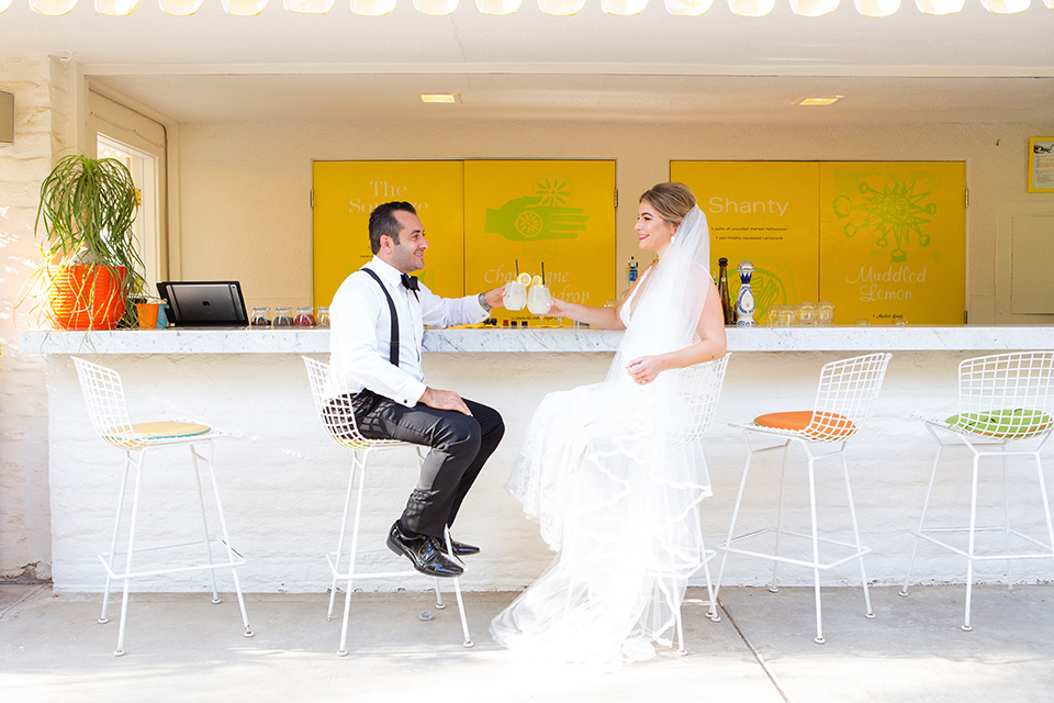 Palm-Springs-wedding-at-the-parker-bride-and-groom-at-bar-bride-in-a-flowing-gown-with-straps-and-a-plunging-deep-v-neckline-groom-in-a-grey-tuxedo-with-black-trim-and-black-pants