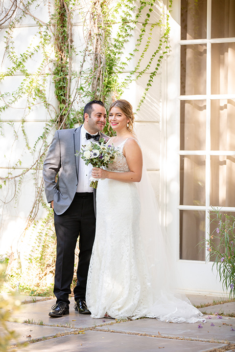 Palm-Springs-wedding-at-the-parker-bride-and-groom-smiling-bride-in-a-flowing-gown-and-a-deep-v-neckline-groom-in-a-grey-tux-with-black-trim-and-black-pants