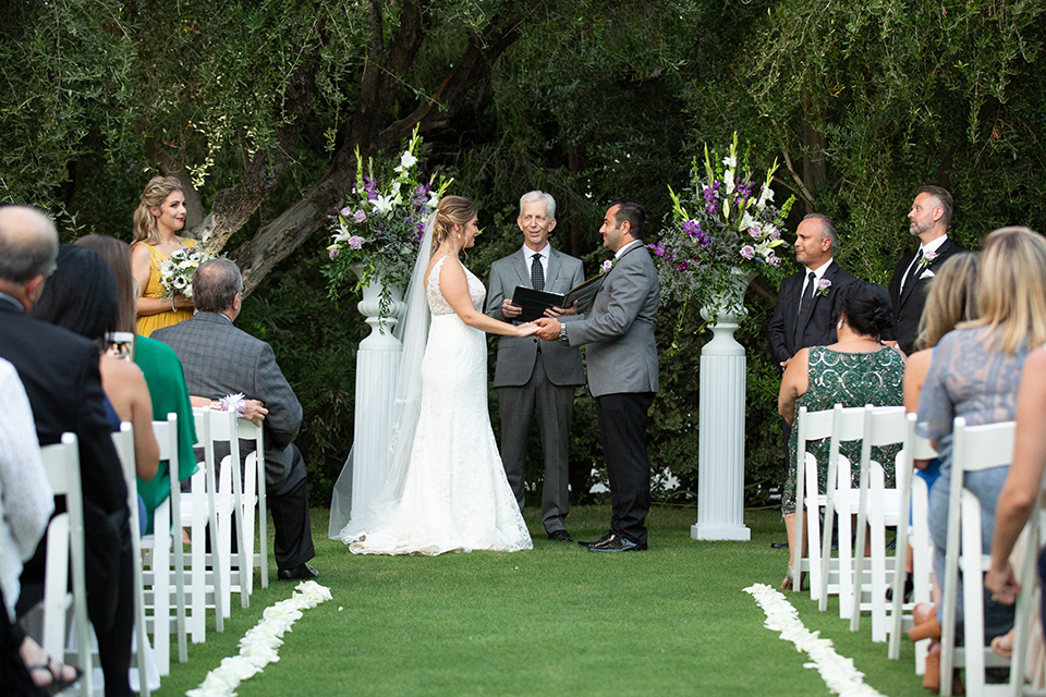 Palm-Springs-wedding-at-the-parker-ceremony-time-bride-in-a-flowing-gown-with-straps-and-a-plunging-deep-v-neckline-groom-in-a-grey-tuxedo-with-black-trim-and-black-pants