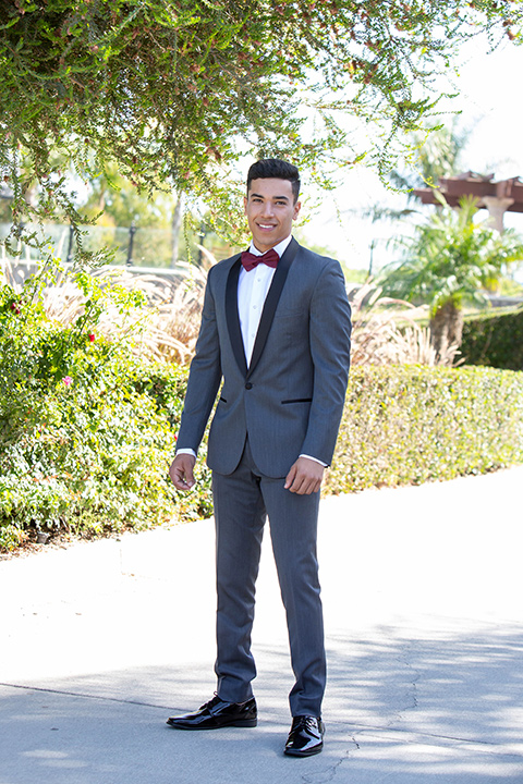 quince-shoot-chambelan-in-royal-themed-tuxedo-in-charcoal-with-a-black-trimmed-lapel-and-burgundy-bow-tie