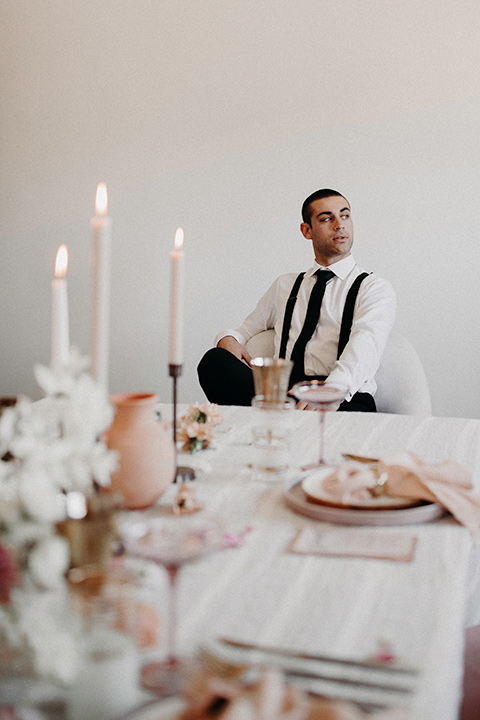 Rim-Rock-Ranch-Shoot-groom-sitting-at-table-groom-in-a-white-shirt-black-pants-and-black-suspenders