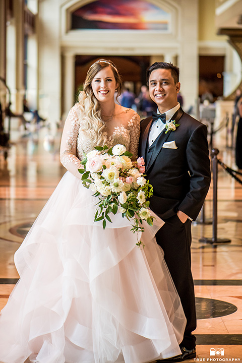 Hyatt-San-Diego-wedding-bride-and-groom-smiling-at-camera-the-bride-in-a-blush-toned-ballgown-and-the-groom-in-a-black-shawl-tuxedo