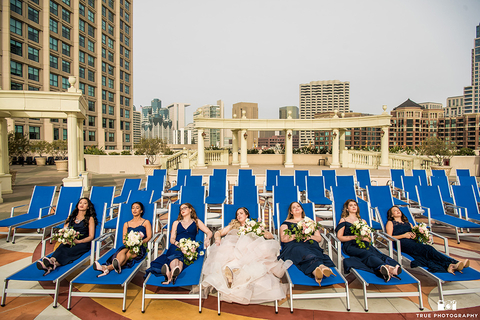 Hyatt-San-Diego-wedding-bridesmaids-on-pool-loungers-in-blue-gowns