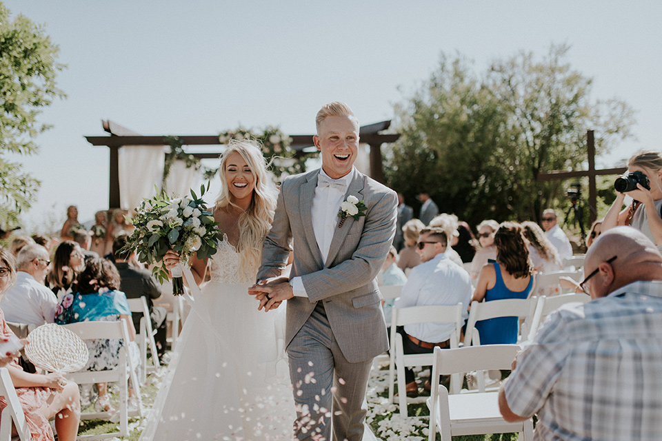 serendiity-gardens-bride-and-groom-after-ceremony-bride-in-a-tulle-ball-gown-with-straps-groom-in-grey-suit-with-brown-susenders-bridesmaids-in-pink-dresses-groomsmen-in-grey-suits