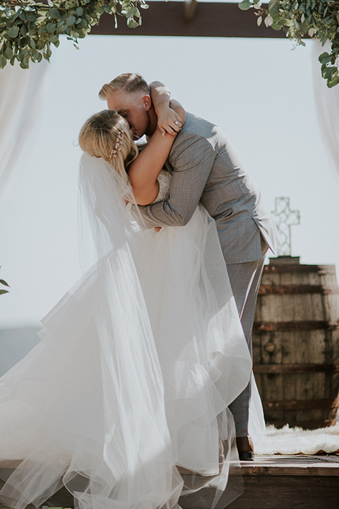 serendiity-gardens-first-kiss-bride-in-a-tulle-ballgown-with-straps-groom-in-a-grey-suit-with-brown-suspenders