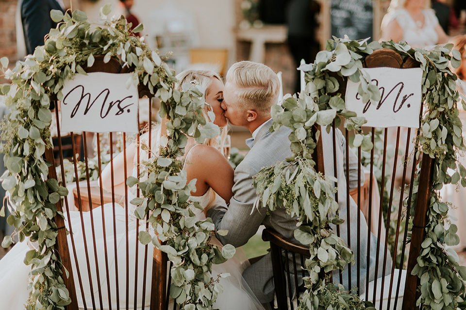 serendiity-gardens-mr-and-mrs-siigns-bride-in-a-tulle-ball-gown-with-straps-groom-in-grey-suit-with-brown-susenders-bridesmaids-in-pink-dresses-groomsmen-in-grey-suits