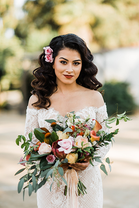 Olivas-Adobe-spanish-inspired-shoot-close-up-on-bride-wearing-a-lace-gown-with-sleeves-and-holding-a-large-bouquet-of-flowers