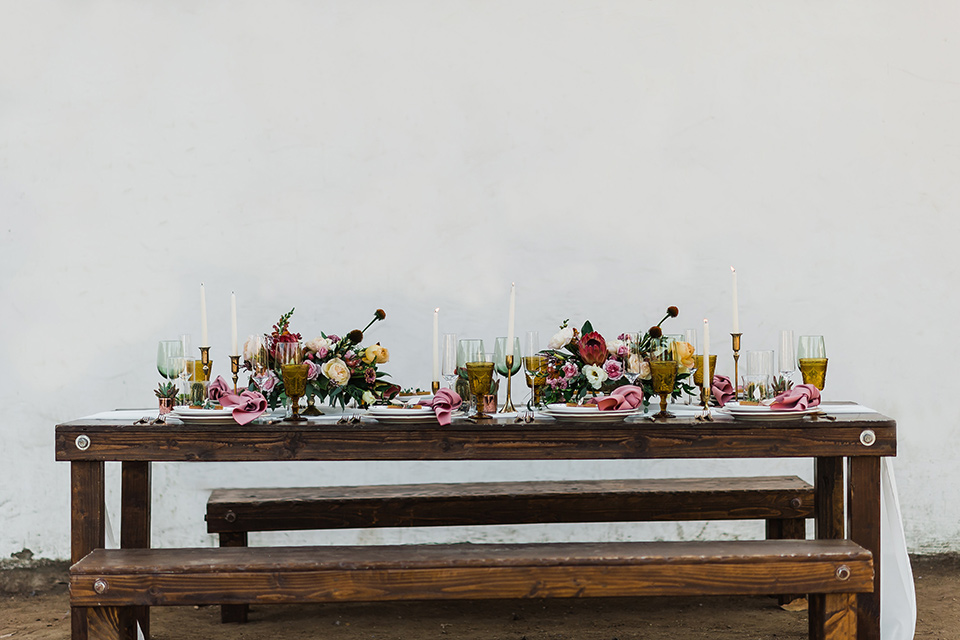 Olivas-Adobe-spanish-inspired-shoot-picnic-table-setting-with-wooden-table-and-white-linens-and-tall-candles