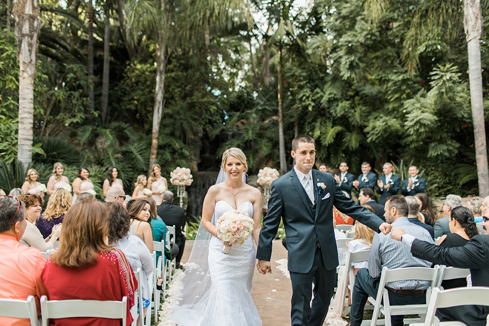 tropical-wedding-at-the-grand-tradition-bride-and-groom-walking-down-aisle-the-bride-was-in-a-trumpet-style-gown-with-a-strapless-neckline-and-the-groom-is-a-navy-suit-with-ivory-tie