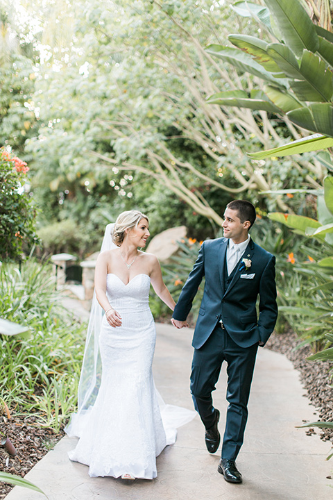 tropical-wedding-at-the-grand-tradition-bride-and-groom-walking-the-bride-in-a-trumpet-style-gown-with-a-sweetheart-neckline-the-groom-in-a-navy-blue-suit