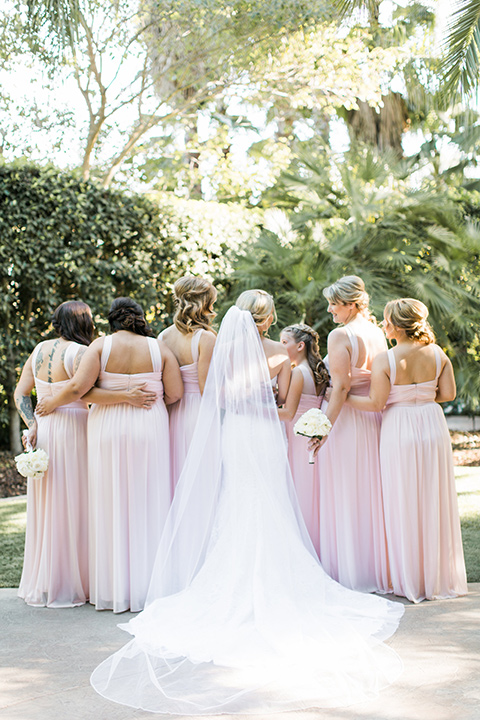 tropical-wedding-at-the-grand-tradition-bridesmaids-back-turned-to-camera-the-bridesmaids-in-pink-gowns-and-the-bride-in-a-white-trumpet-style-gown