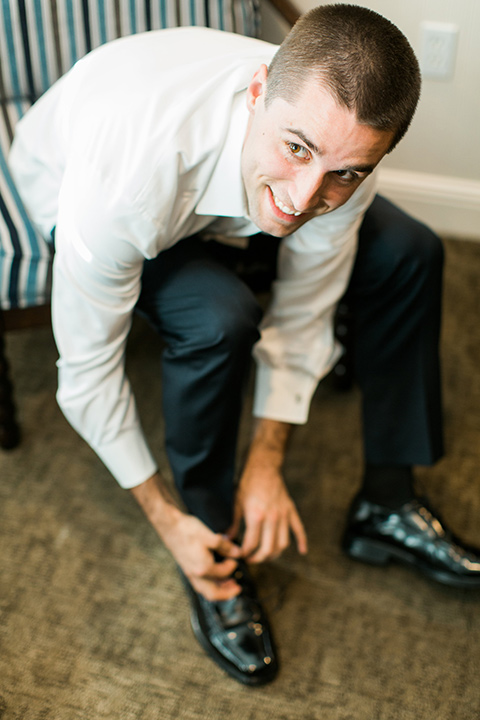 tropical-wedding-at-the-grand-tradition-groom-tying-shoes