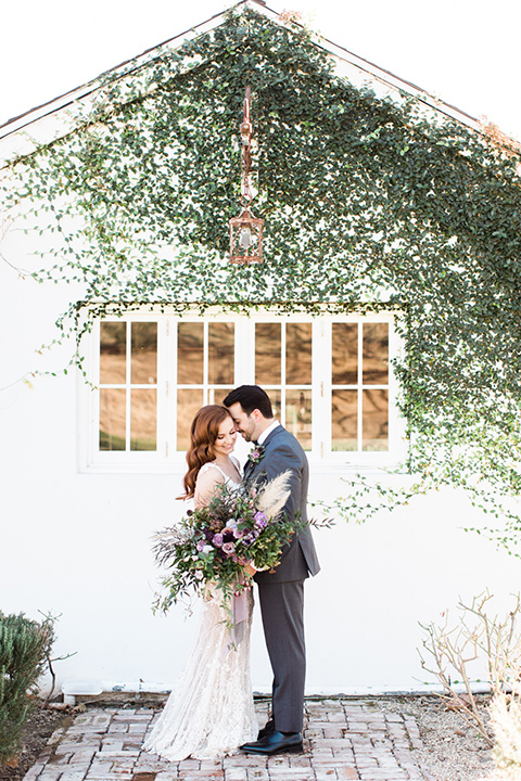 triunfo-creek-vineyards-wedding-bride-and-groom-outside-with-ivy-in-background-bride-wearing-a-flowing-ivory-and-blush-gown-with-straps-and-a-sweetheart-neckline-groom-in-a-charcoal-grey-suit-with-a-lack-bowtie