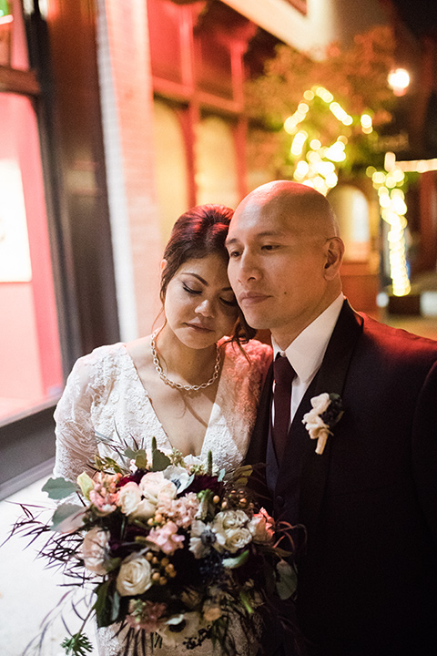 villa-del-sol-wedding-bride-and-groom-close-bride-in-a-spanish-inspired-lace-gown-with-sleeves-groom-in-a-navy-shawl-lapel-tuxedo-with-a-burgundy-tie