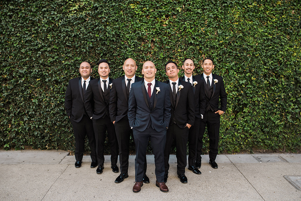 villa-del-sol-wedding-groomsmen-groom-in-a-navy-shawl-lapel-tuxedo-with-a-burgundy-tie-groomsmen-in-black-shawl-lapel-tuxedos