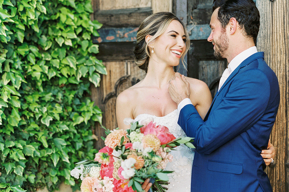 whispering-rose-shoot-bride-and-groom-looking-at-each-other-bride-wearing-a-strapless-gown-with-pink-shoes-groom-in-a-cobalt-blue-suit-with-brown-shoes-and-an-ivory-tie