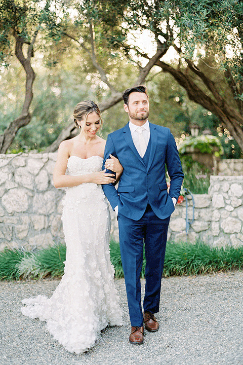 whispering-rose-shoot-bride-and-groom-walking-bride-wearing-a-strapless-gown-with-pink-shoes-groom-in-a-cobalt-blue-suit-with-brown-shoes-and-an-ivory-tie