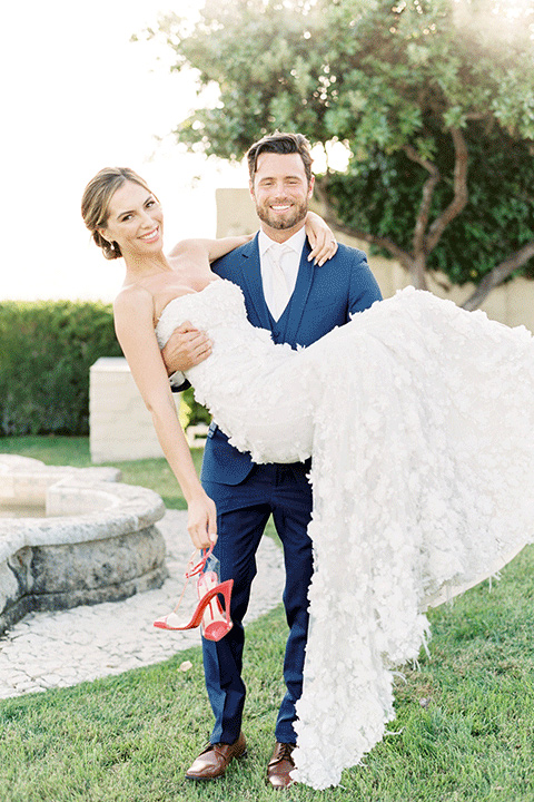 whispering-rose-shoot-groom-holding-bride-bride-wearing-a-strapless-gown-with-pink-shoes-groom-in-a-cobalt-blue-suit-with-brown-shoes-and-an-ivory-tie