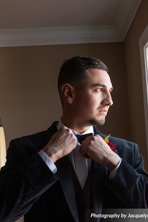  groom in a black velvet tuxedo with a black bow tie