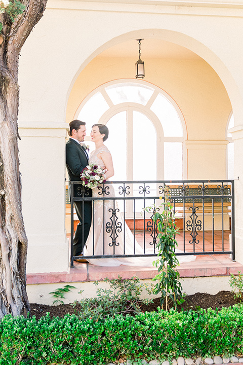  bride in a Spanish style white lace gown with sleeves and dee red lipstick groom in a deep green suit with a tan bow tie