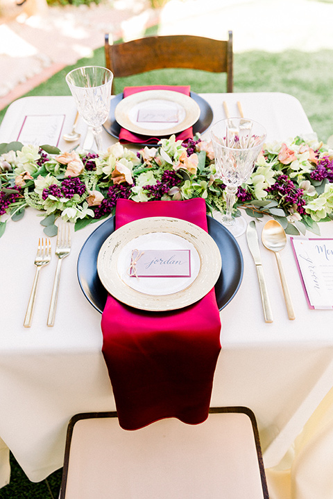  white table linens with red and black pates and gold flatware