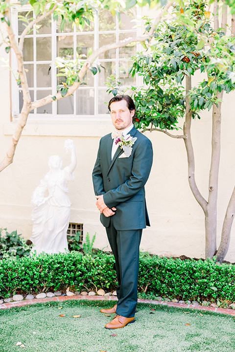  groom in a deep green suit with a tan bow tie