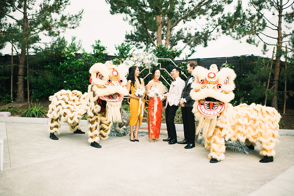  bride in a white gown with a strapless neckline and the groom in an ivory paisley tuxedo with a black bow tie with dragons outside