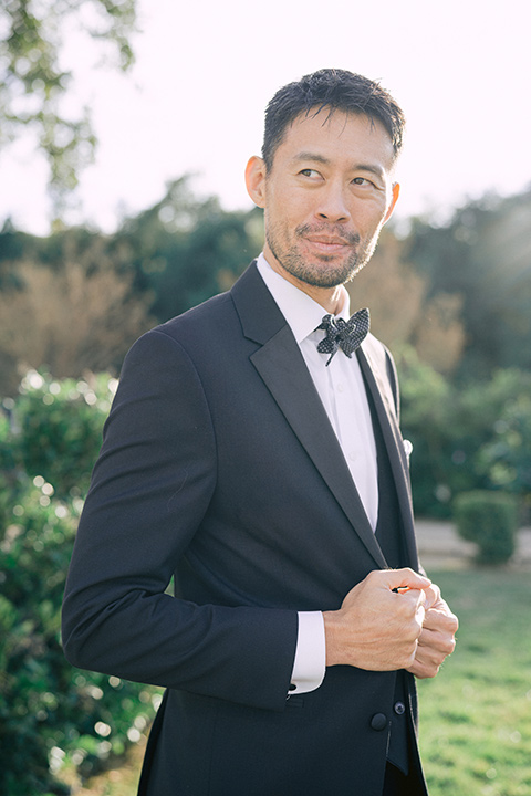  The groom in a black michael kors tuxedo with a black bow tie 