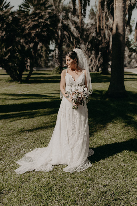  bride in a white lace gown with a v neckline and an elbow length veil 