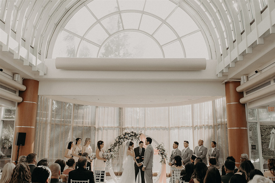  bride and groom at the ceremony with wide windows and arch 