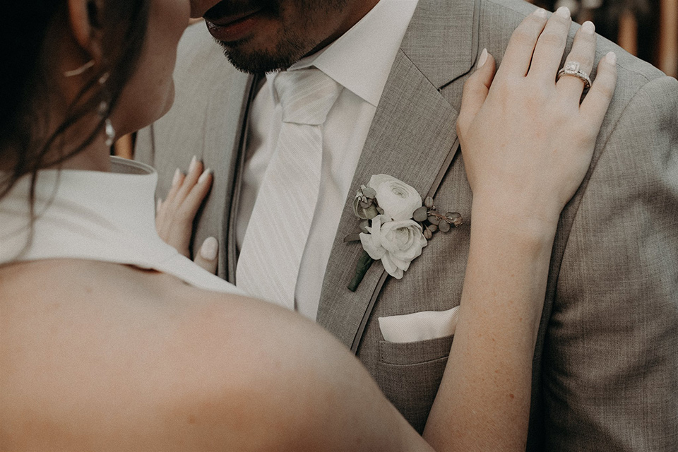  bride in a modern white gown with a high neckline, the groom in a light grey suit with a notch lapel and a white long tie