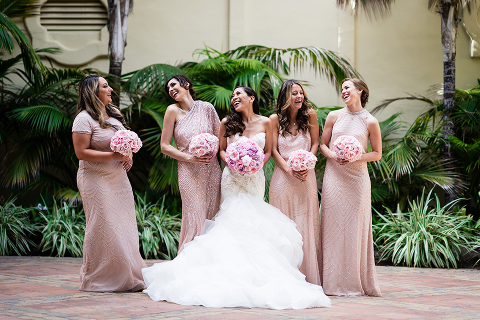  The bride in a mermaid style gown with a sweetheart neckline the bridesmaids are in rose gold blush gowns