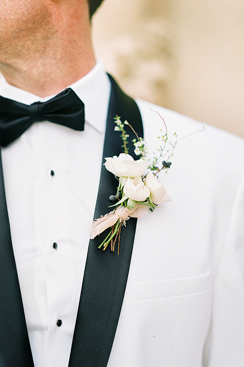 groom in a white shawl lapel tuxedo with a black bow tie