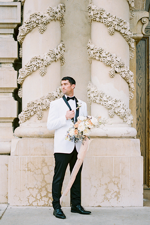  groom in a white shawl lapel tuxedo with a black bow tie