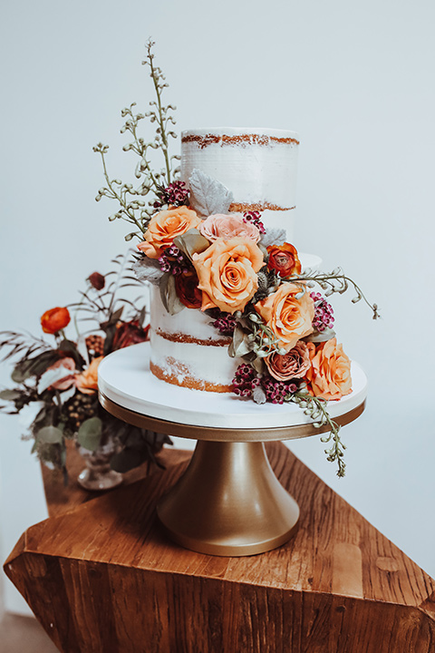  a white natural frosted cake with orange and green flowers 