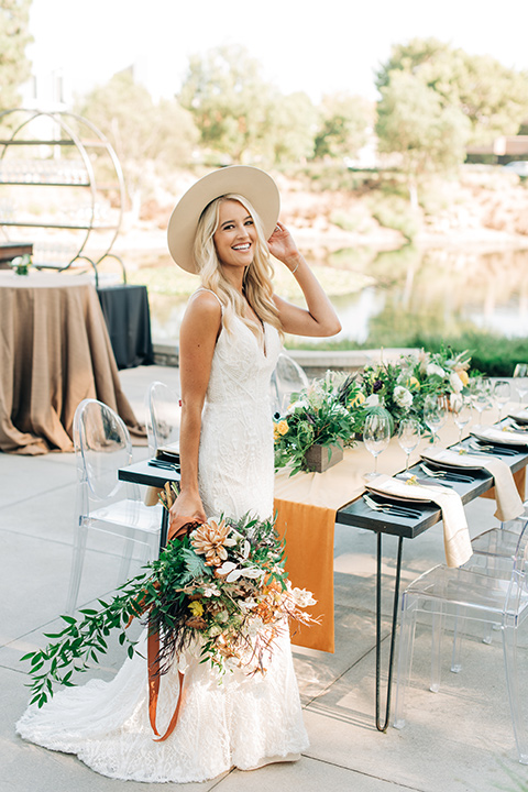  bride in a white lace bohemian style wedding gown with a tan wide brimmed hat