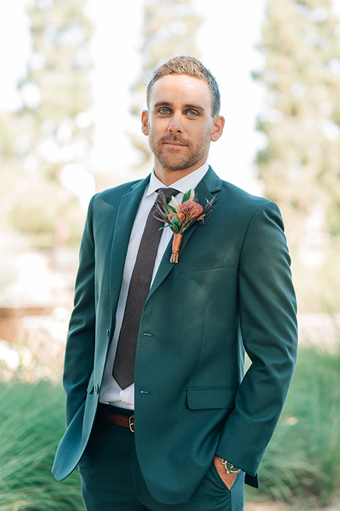  the groom in a dark green suit with a chocolate long tie 
